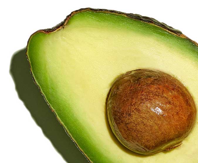 An open avocado with seed inside on a white background