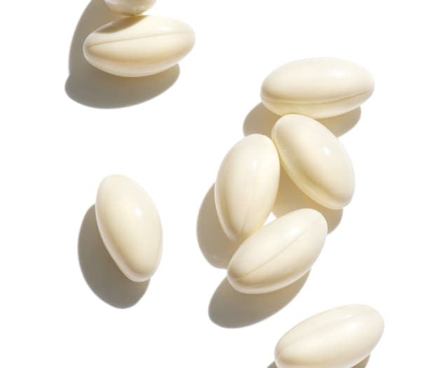 Beige biotin capsules on white background. 